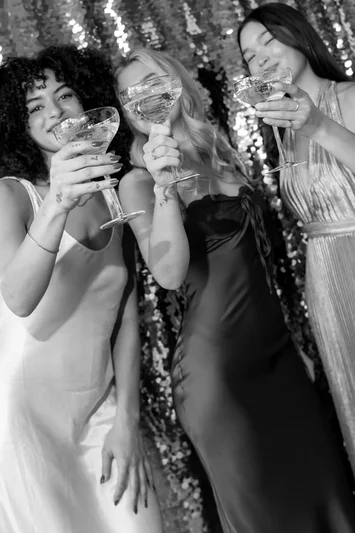 Wedding guests in formal dress raising champagne glasses in a black and white photo strip