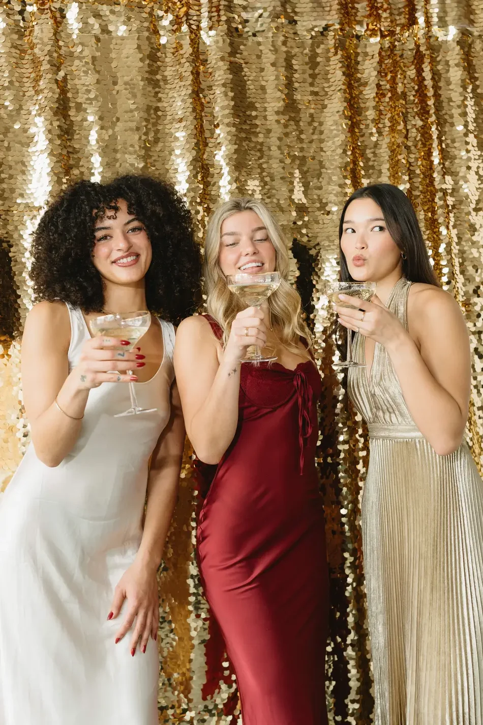 Friends celebrating in front of the gold sequin backdrop at a garden wedding